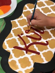 using a paint brush to hand letter a door hanger