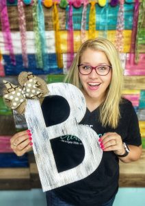 Tamara holding a painted letter B door hanger with a burlap bow