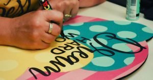 Tamara hand lettering words on a polka dot door hanger