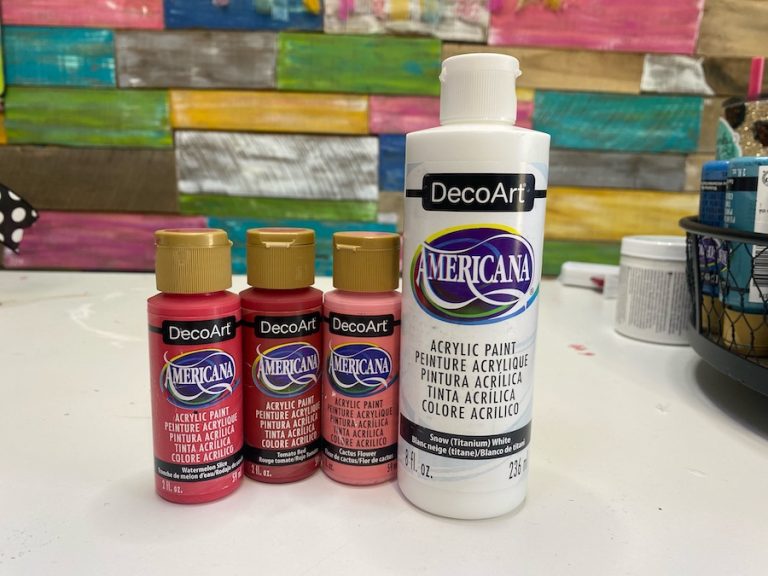 four bottles of paint used to paint the wood sign