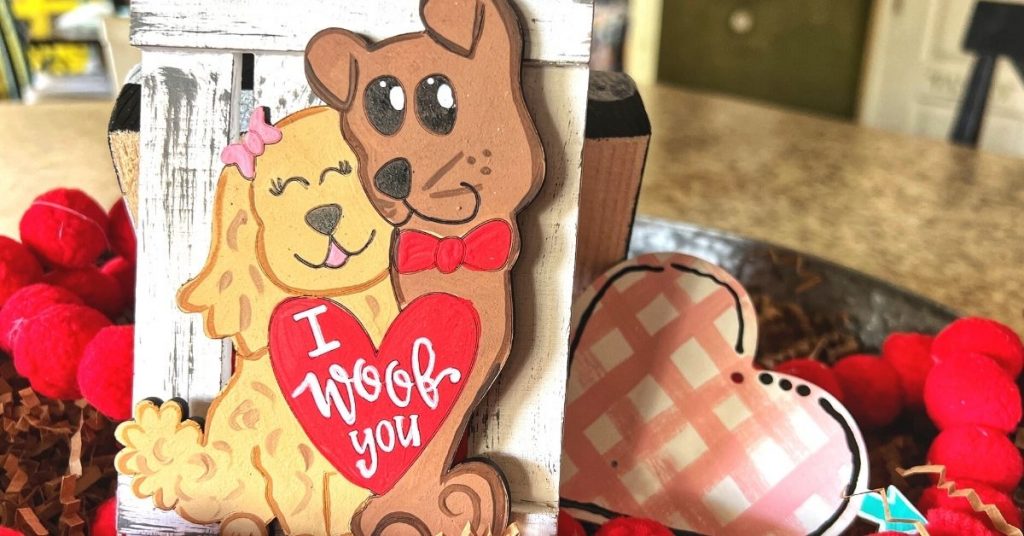 Two puppies on a wooden background with a heart that says "I woof you"