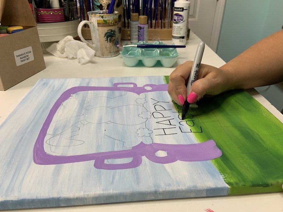 Tamara using a Sharpie to trace the lettering on the canvas template