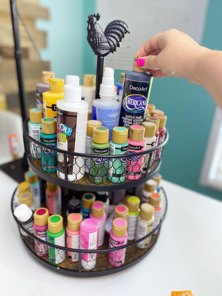 hand reaching for a paint bottle in a tiered tray