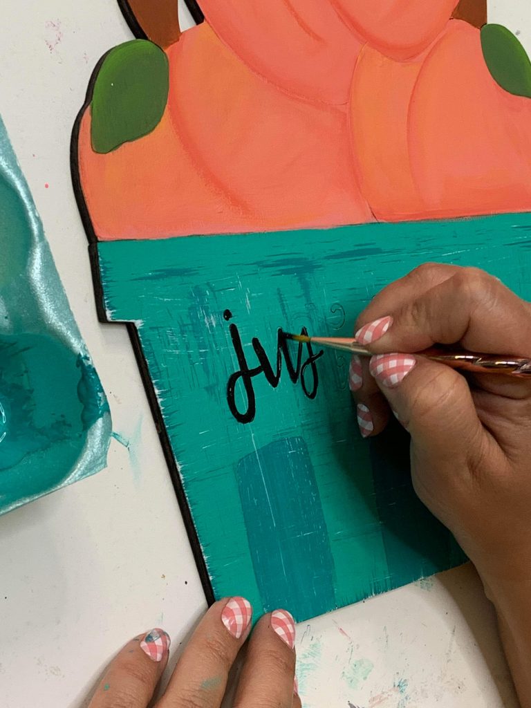 adding hand lettering to the basket of peaches