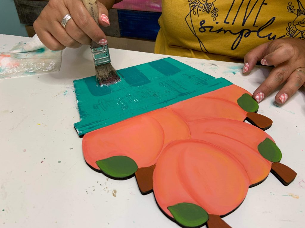 painting the basket of the door hanger with a paint brush