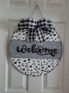 Leopard print door hanger that reads "welcome" and has a buffalo plaid bow