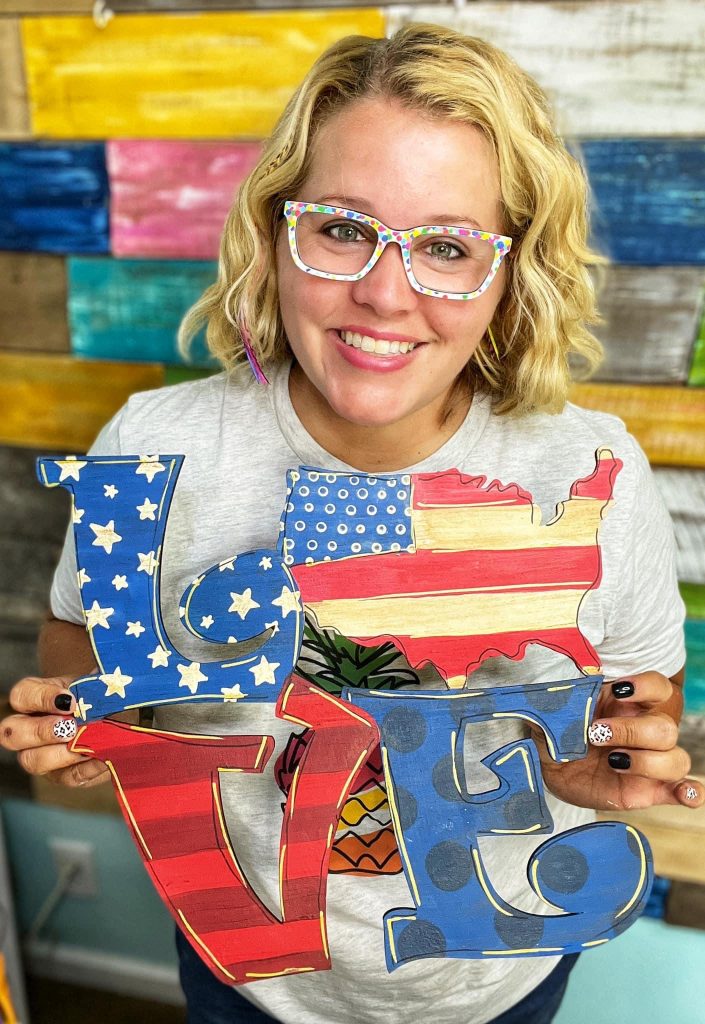 Tamara Bennett holding a patriotic door hanger
