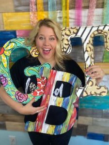 Tamara holding three wooden letters painted with different patterns