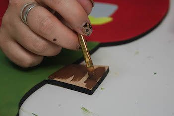 Painting the Christmas tree trunk using brown paint and a small brush