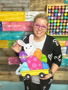 Tamara holding a door hanger of a wagon with a bunny and Easter Eggs in it