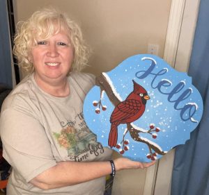 Sandy McQurter holding a cardinal door hanger