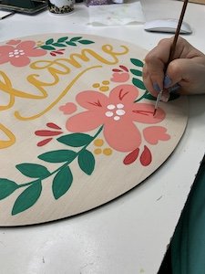 painting the details of the welcome flowers door hanger