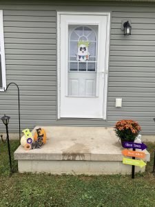 front porch with boo babe door hanger on door and mums with fall signs